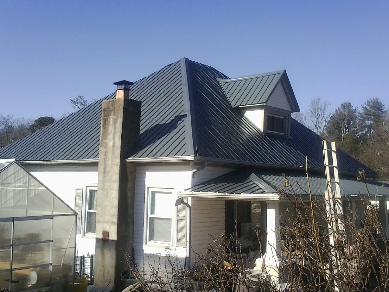 Dark blue standing seam metal roof on a white farmhouse with dormer — Slate & Tile Roof Repair by Roofing Brothers in Phillipsport