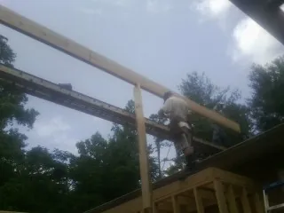 Carpenter setting a ridge beam over a new addition frame — Ice Dam Removal by Roofing Brothers in Phillipsport