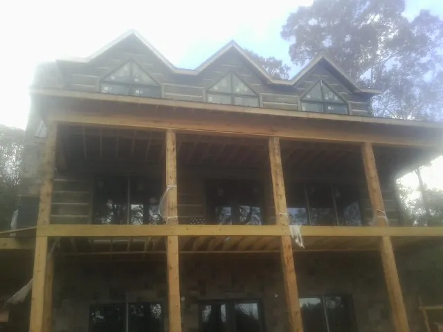 Dormers and porch framing on a large log home under construction — Roof Coating work by our crew in Phillipsport