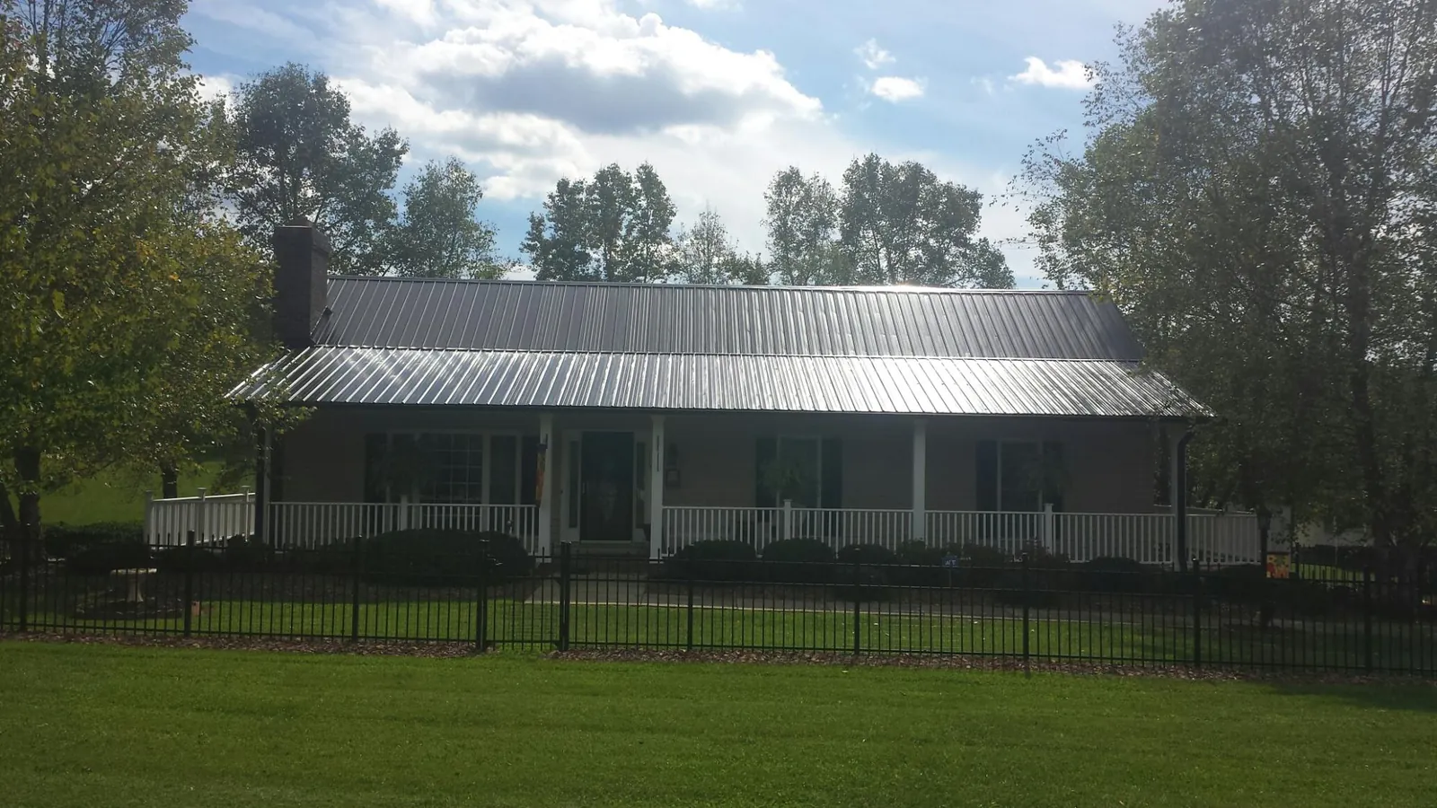 Gray metal roof on a brick ranch with a full width front porch — Gutter Guard Installation work by our crew in Phillipsport
