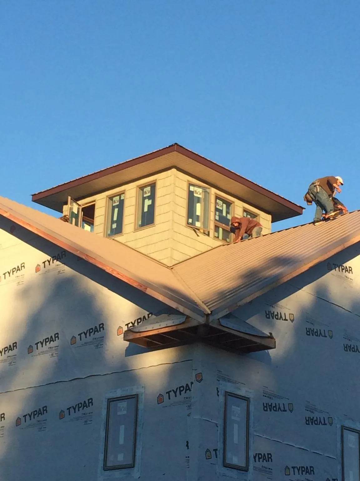 Roofers working around a rooftop cupola on a new metal roof at sunset — Roof Waterproofing in Phillipsport by Roofing Brothers